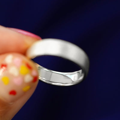 A model holding a solid silver Mix Stardust Band tilted to show the inside of the band