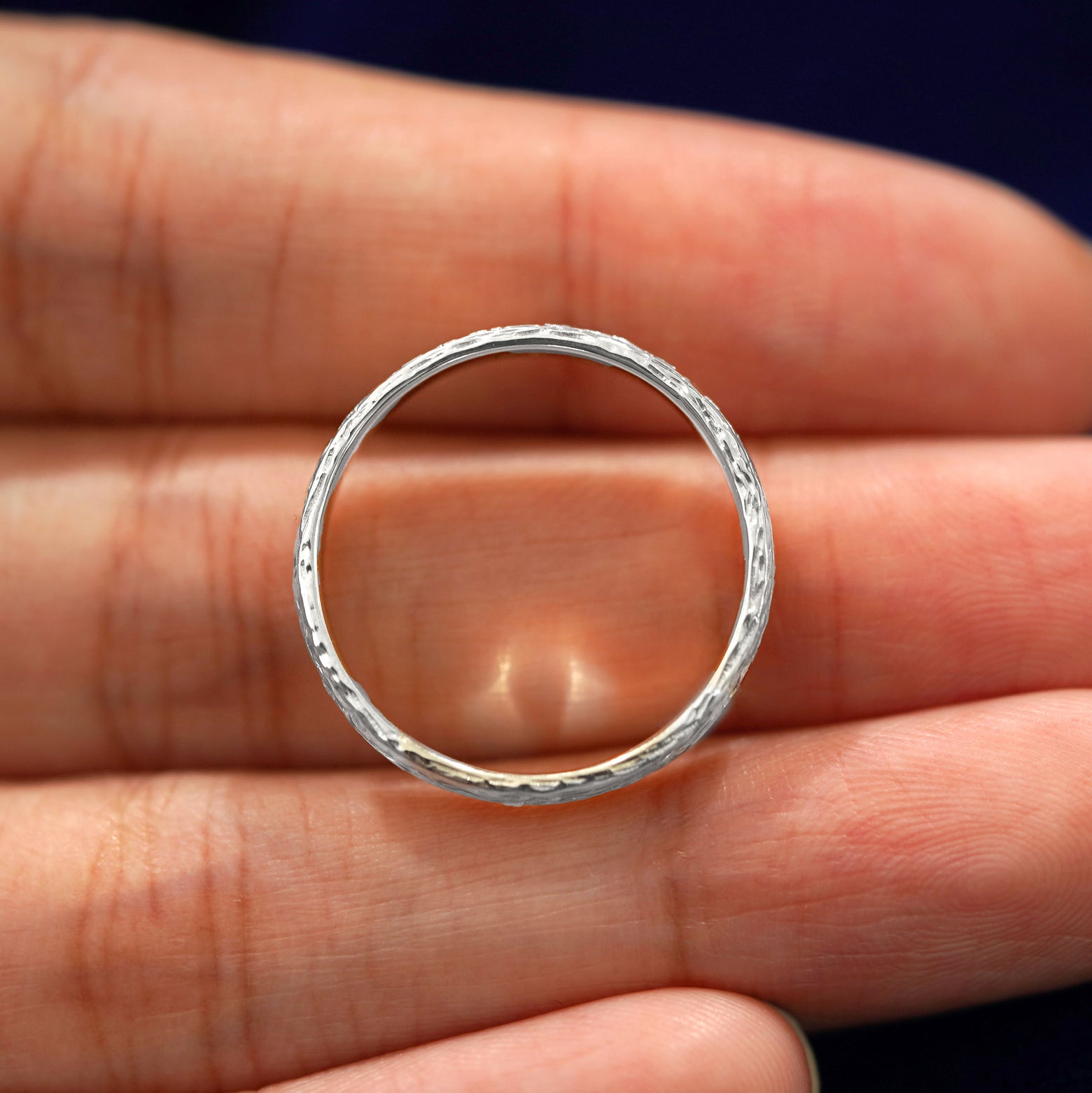 A silver Raw Band in a model's hand showing the thickness of the band

