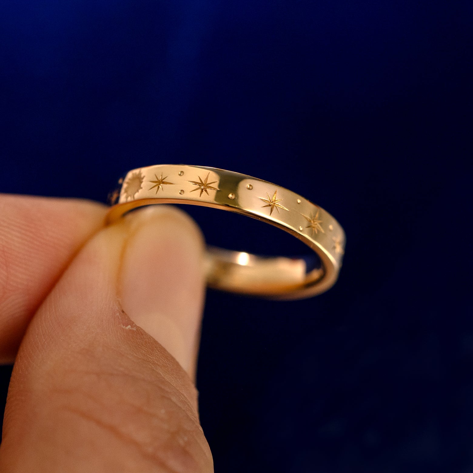 A model holding a Industrial Sun Moon and Stars Band up to show the details of the design and the inside of the ring