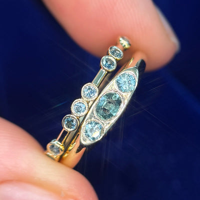 14k Yellow gold and 0.32ctw Oval with two Round Teal Sapphires Signet Custom Ring and 14k Yellow Gold Asymmetrical Spaced-out Bezel-set 8pc Teal Sapphires All around on thin Band Custom Ring, size 6.25