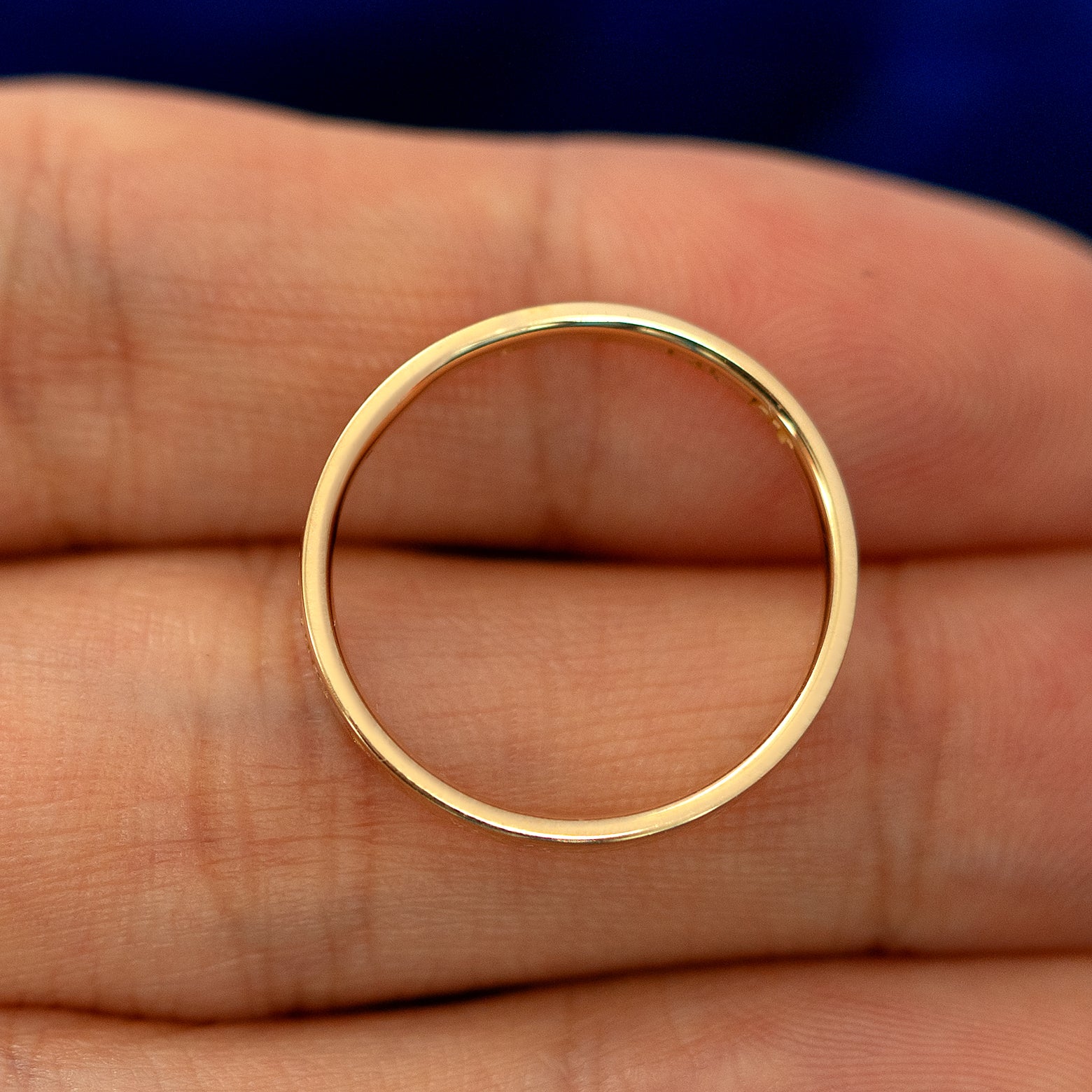 A flush gemstone industrial band laying flat in a models hand to show the thickness of  the band