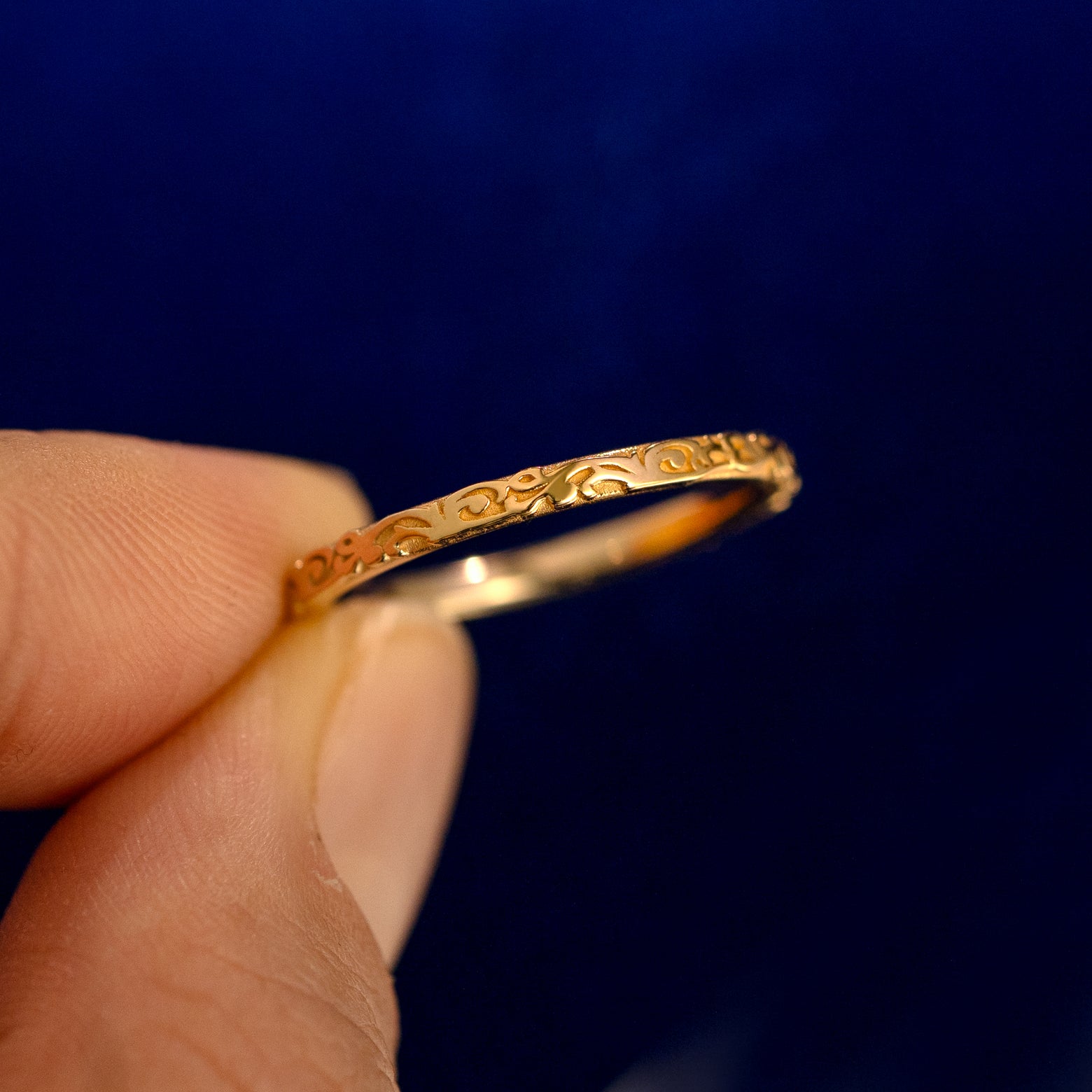 A model holding a Thin Filigree Band up to show the details of the design and the inside of the ring