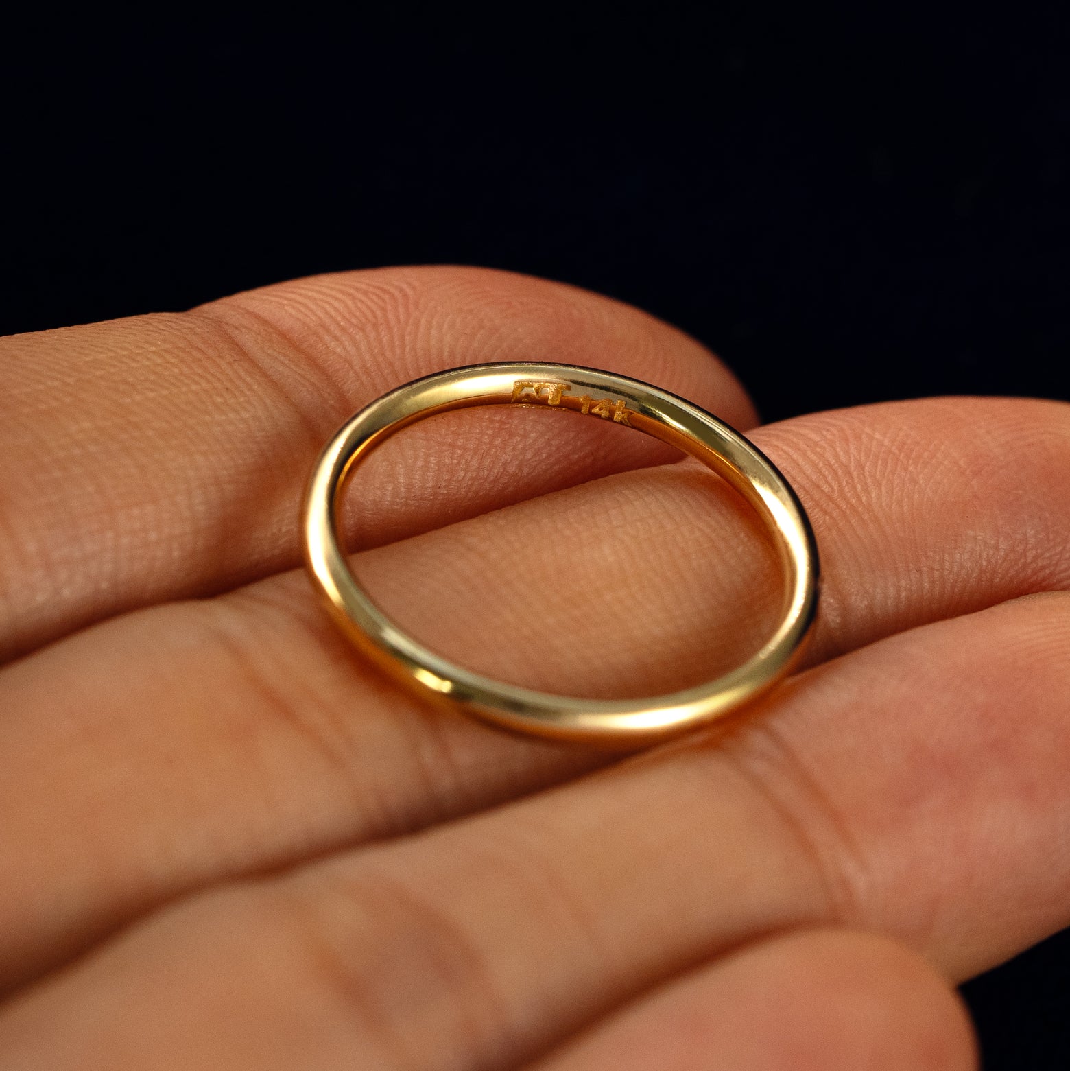 A Flush Set Round Diamond Ring in a model's hand showing the inside of the band