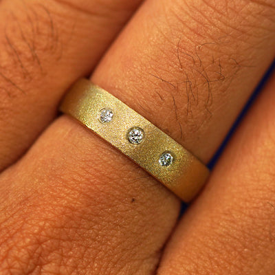 Close up view of a model's fingers wearing a 14k yellow gold Mix Stardust Band with three diamonds