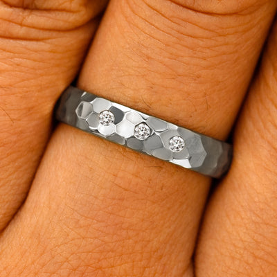 Close up view of a model's fingers wearing a Platinum Curvy Hammered Band with three diamonds