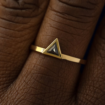 Close up view of a model's hand wearing a 14k yellow gold Triangle Black Diamond Ring