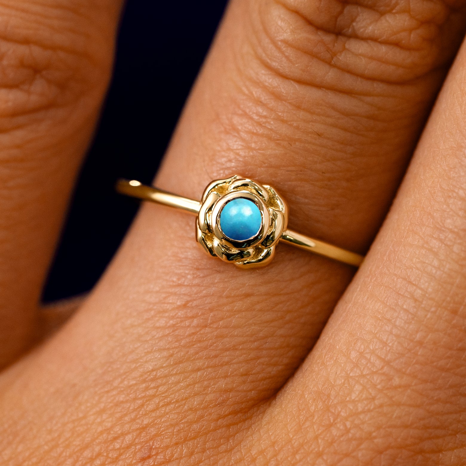 A solid 14k yellow gold Turquoise Gemstone Flower Ring on a model's finger