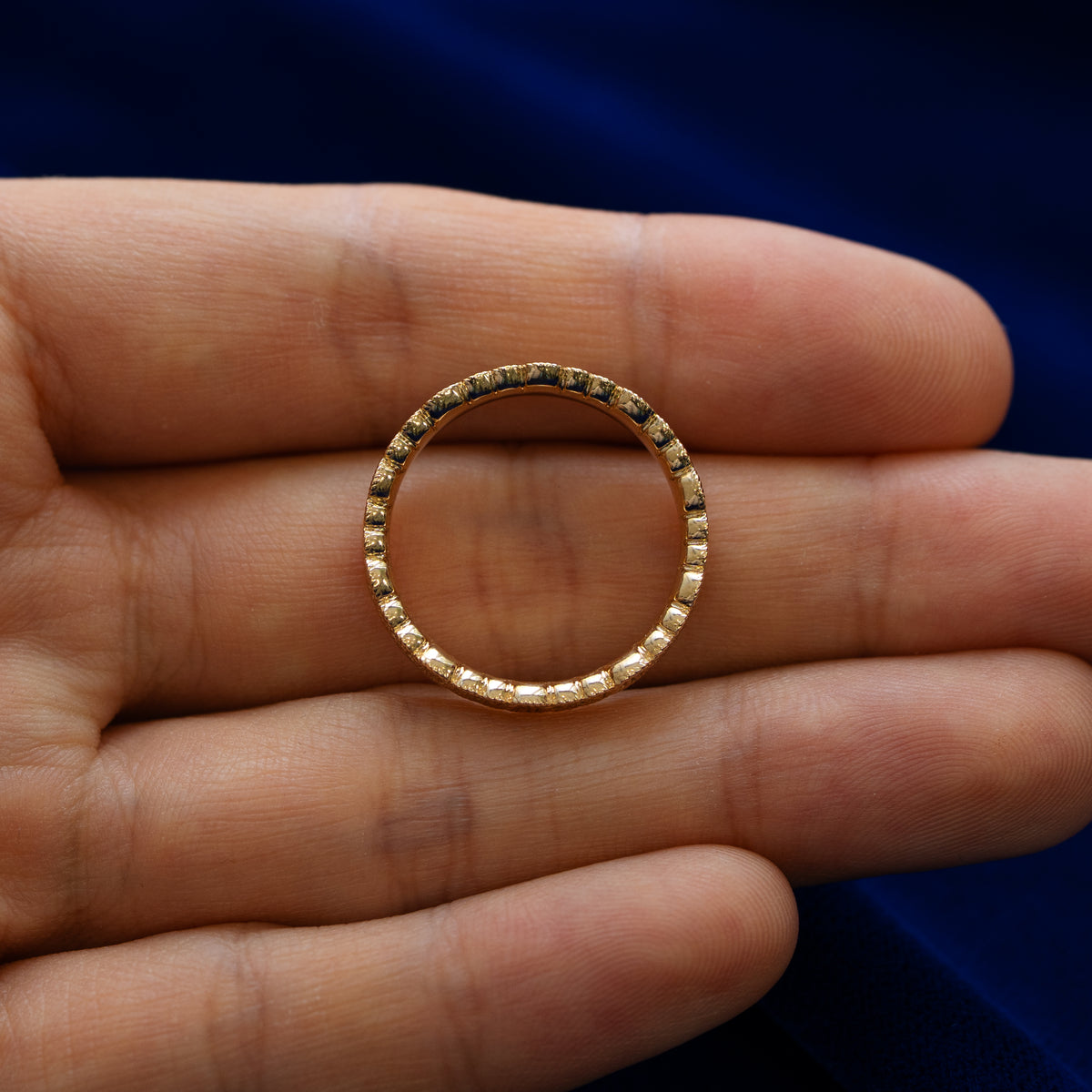 A model holding a milgrain scroll band between two fingers to show engraved pattern details