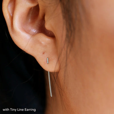 Close up view of a model's ear wearing a white gold Line Jacket with a Tiny Line Earring