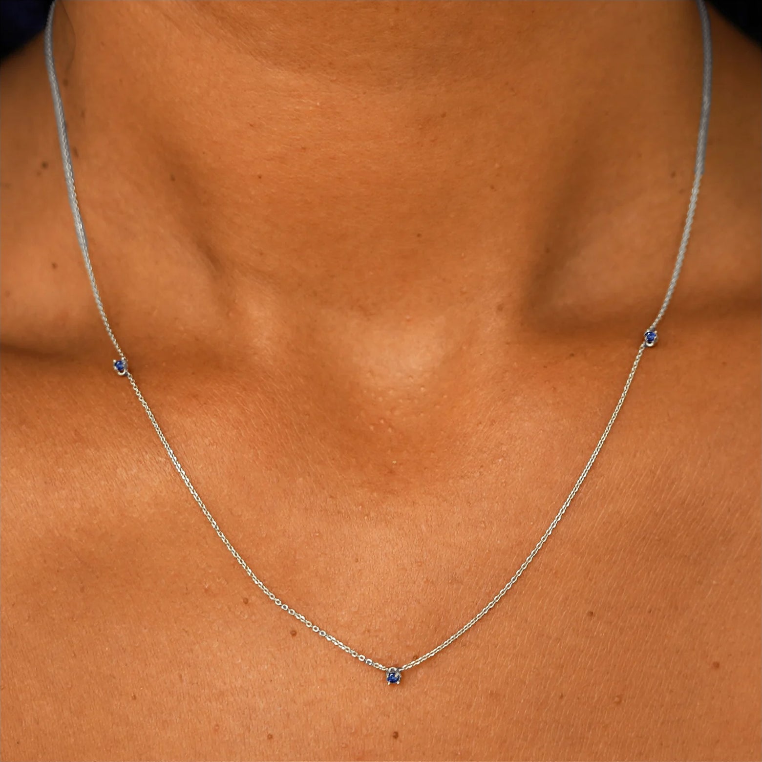 Close up view of a model's neck wearing a solid 14k white gold 3 Gemstone Cable Necklace in sapphire