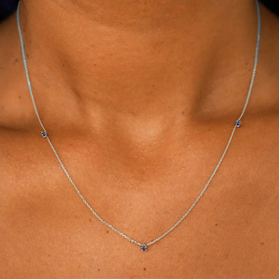 Close up view of a model's neck wearing a solid 14k white gold 3 Gemstone Cable Necklace in sapphire