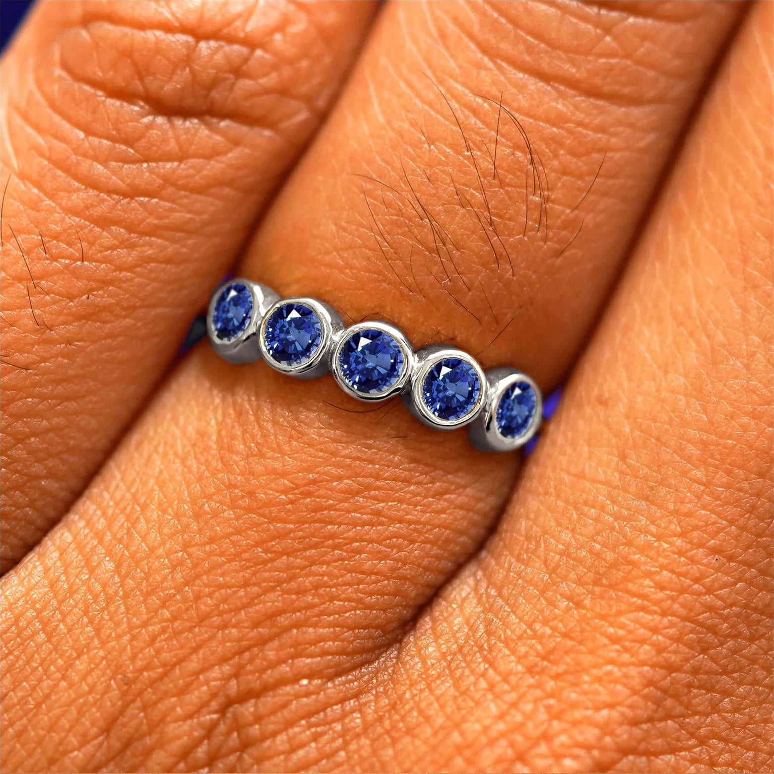 Close up view of a model's hand wearing a white gold 5 Gemstones Ring in sapphires