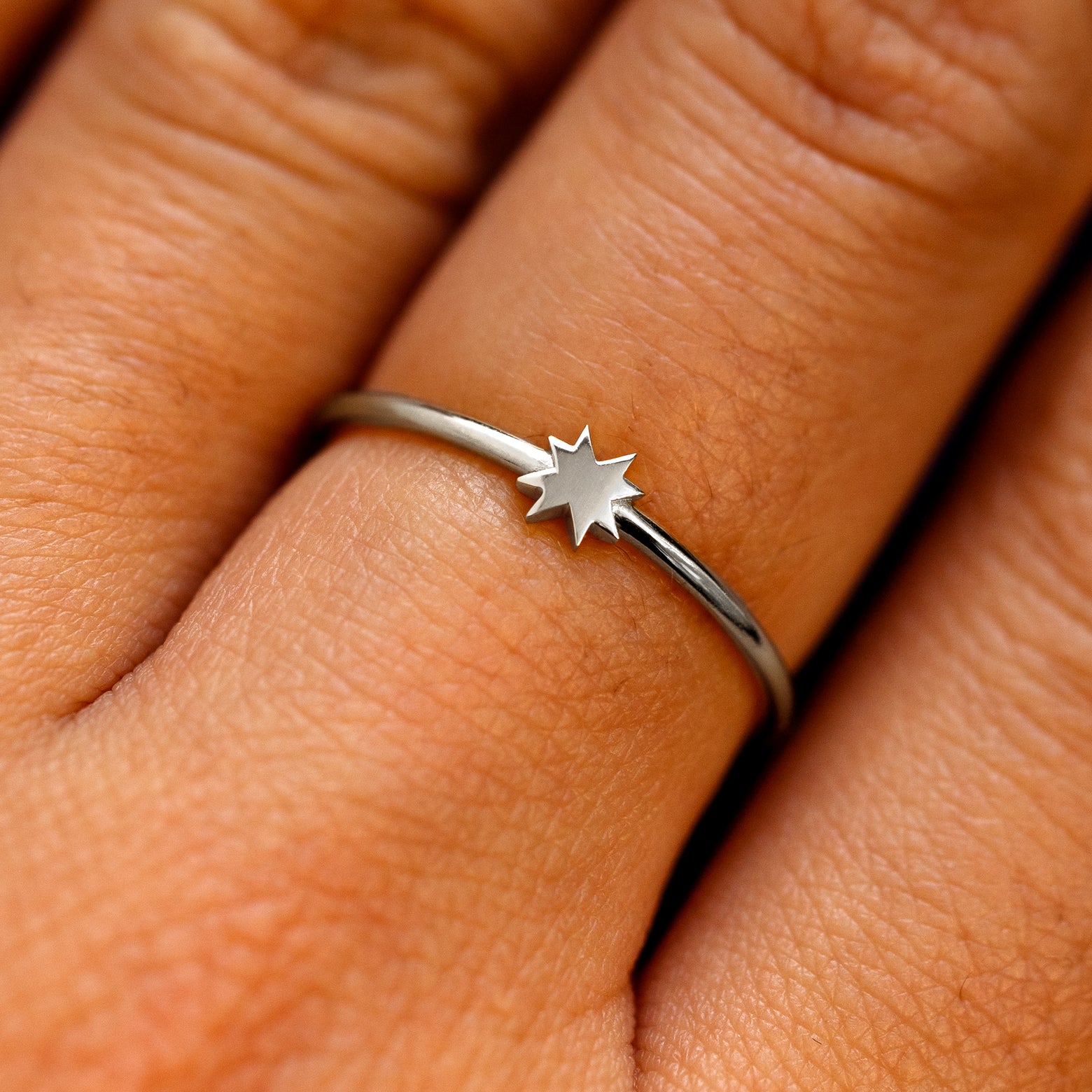 Close up view of a models fingers wearing a white gold 8 pointed star ring