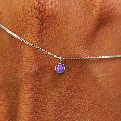 Close up view of a 14k white gold Amethyst Necklace draped across the back of a model's hand