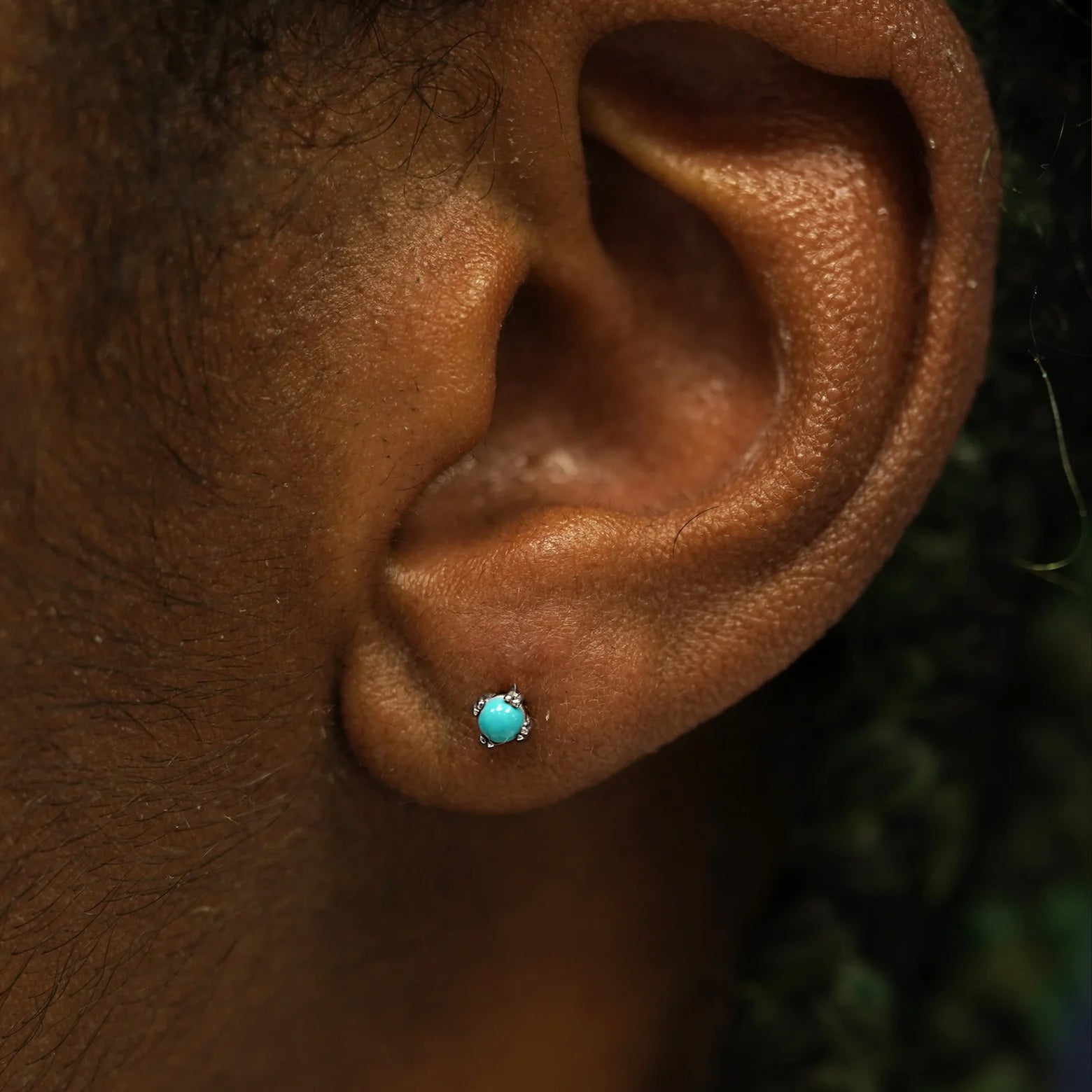 Close up view of a model's ear wearing a 14k white gold turquoise 3mm Gemstone Earring