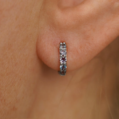 Close up view of a model's ear wearing a white gold Mini Alexandrite Huggie Hoop