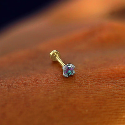 A solid 14k white gold Alexandrite Flatback Piercing resting on the back of a model's hand