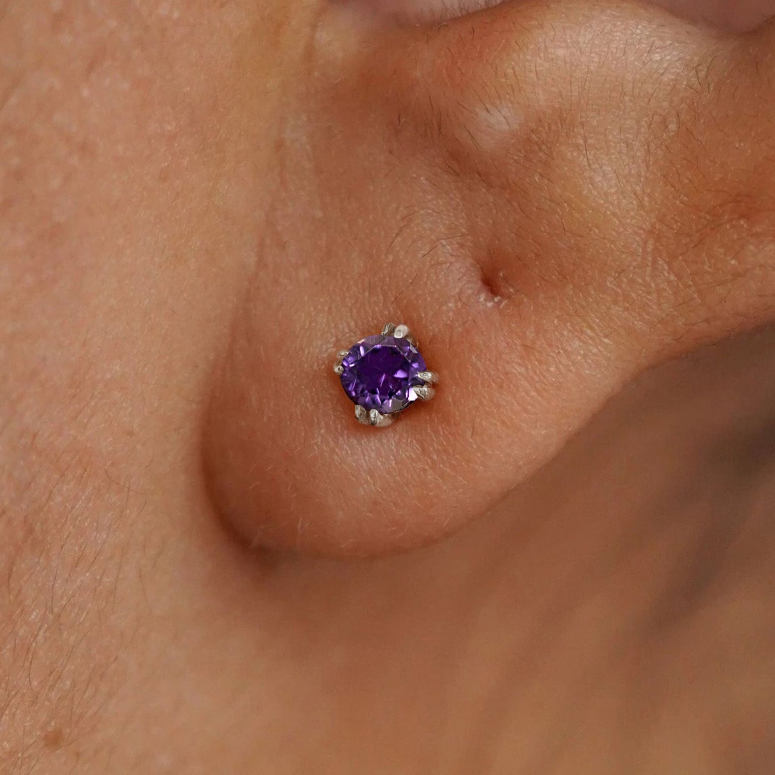 Close up view of a model's ear wearing a 14k white gold Amethyst Stud Earring
