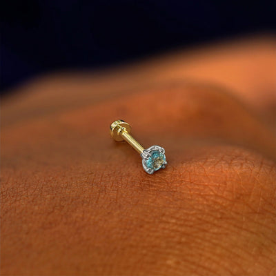 A solid 14k white gold Aquamarine Flatback Piercing resting on the back of a model's hand