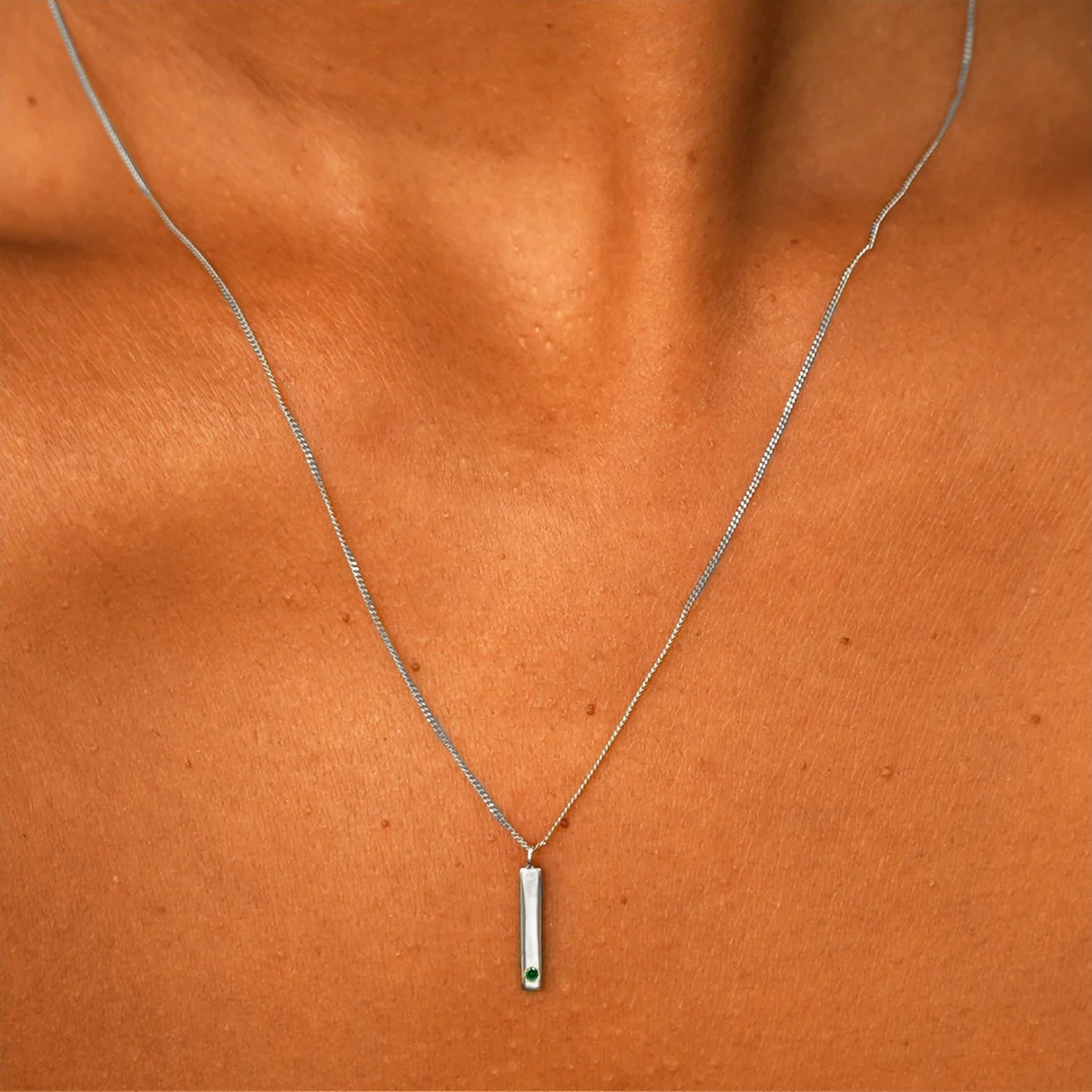 Close up view of a model's neck wearing a solid white gold emerald Gemstone Bar Necklace