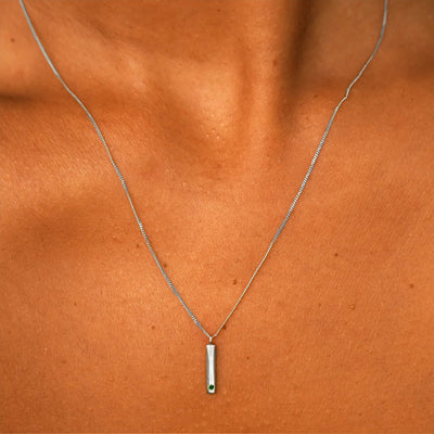 Close up view of a model's neck wearing a solid white gold emerald Gemstone Bar Necklace