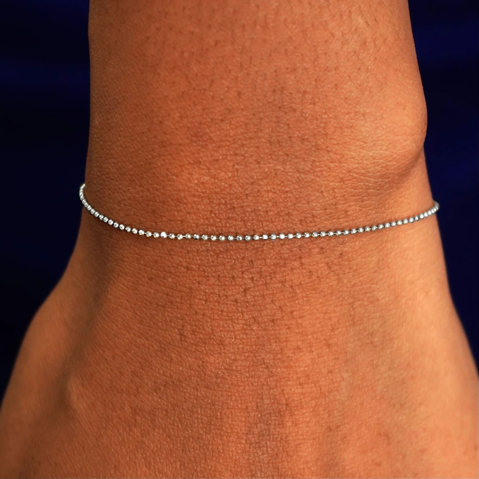 A model's wrist wearing a solid white gold Bead Bracelet