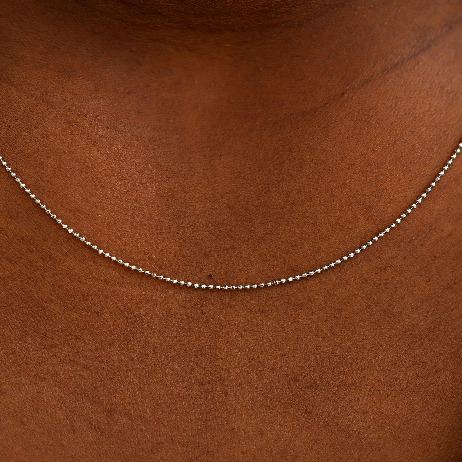 Close up view of a model's neck wearing a solid white gold Bead Chain