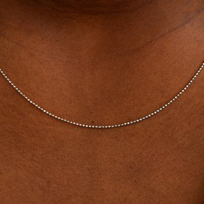 Close up view of a model's neck wearing a solid white gold Bead Chain