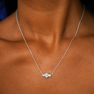 Close up view of a model's neck wearing a solid 14k white gold Bee Necklace