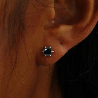 Close up view of a model's ear wearing a white gold black 5mm Moissanite Earring