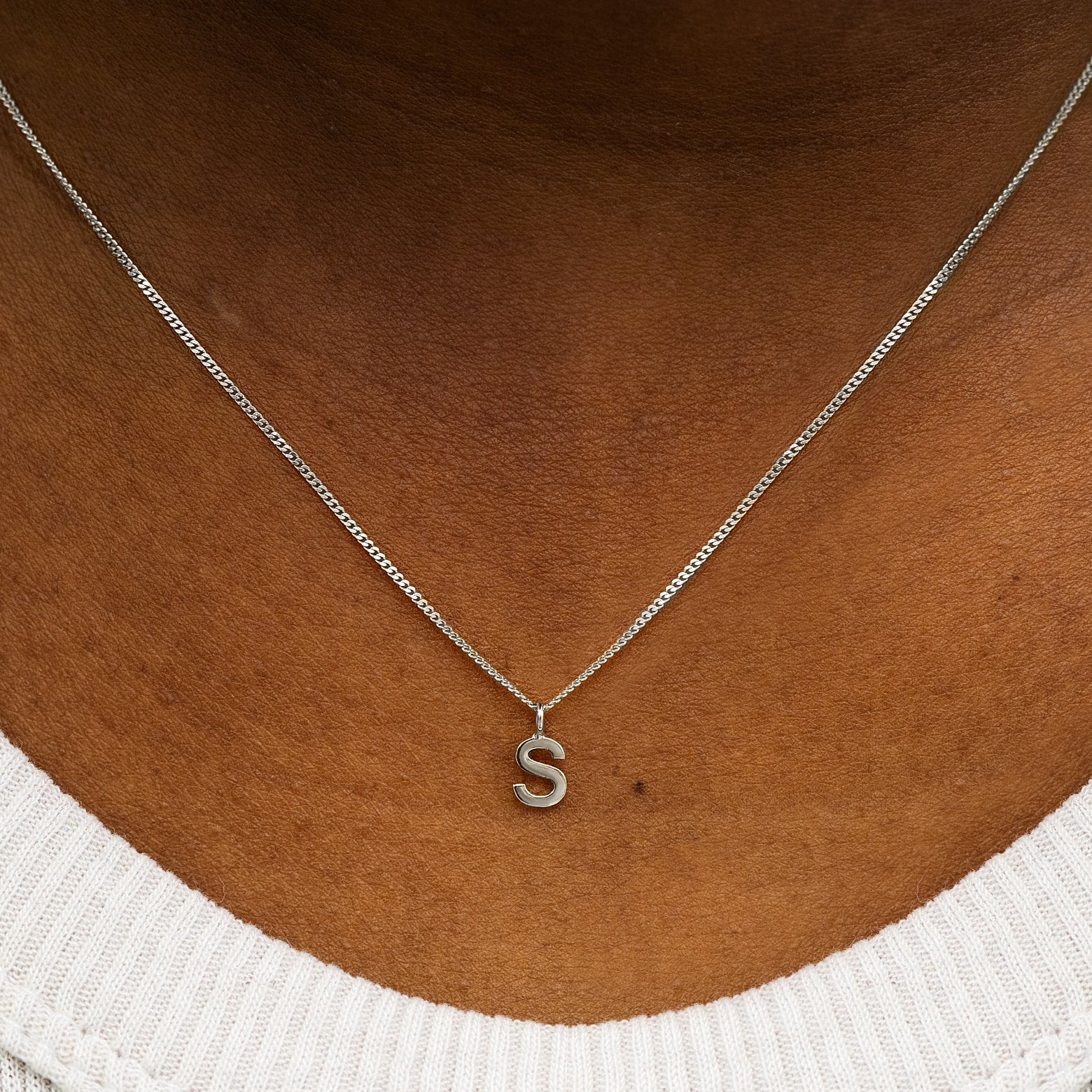 Close up view of a model's neck wearing a 14k solid white gold Block Initial Charm Necklace in the letter S