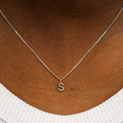 Close up view of a model's neck wearing a 14k solid white gold Block Initial Charm Necklace in the letter S