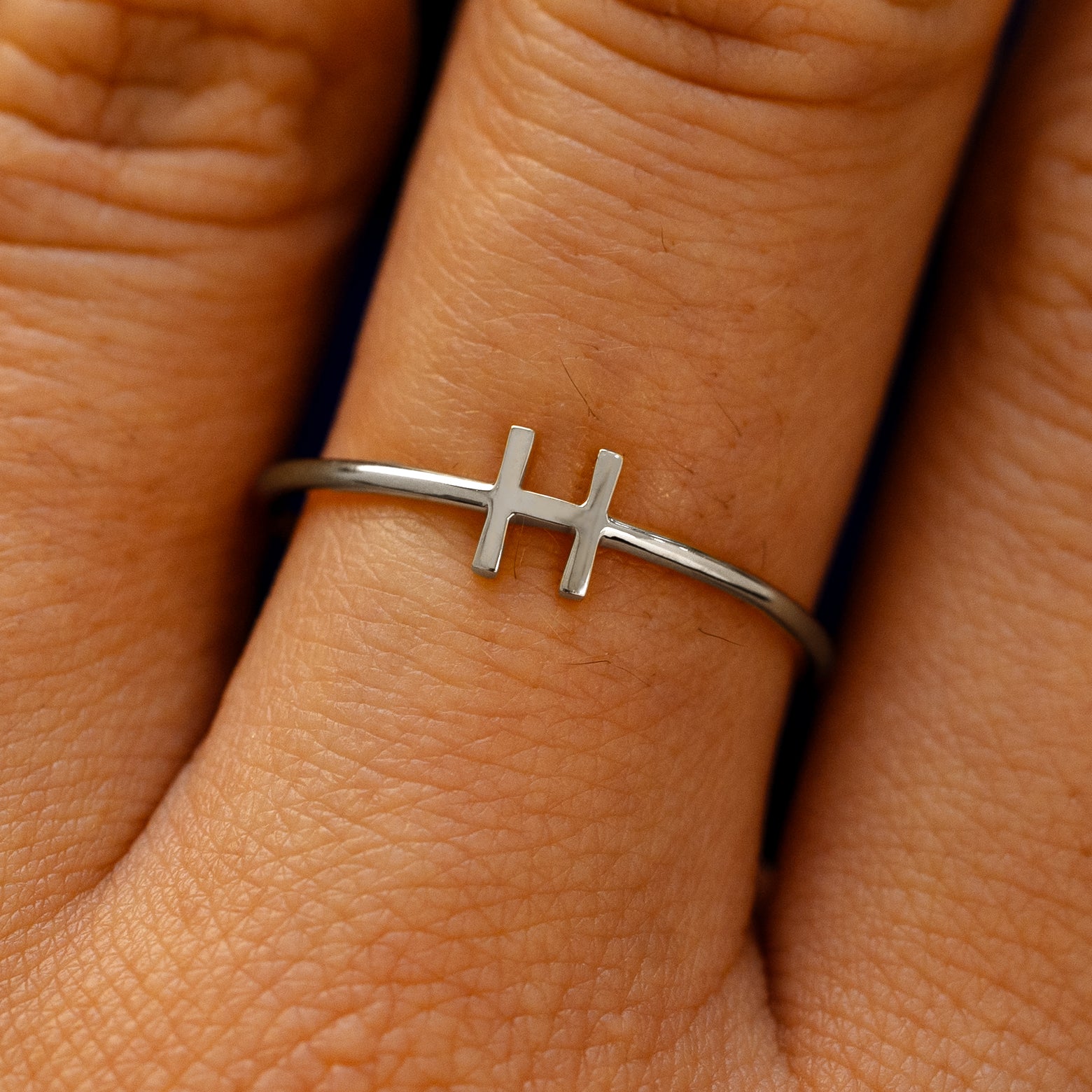 Close up view of a model's fingers wearing a 14k white gold block initial Ring with the letter H