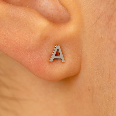 Close up view of a models ear wearing a 14k white gold letter A block initial stud earring