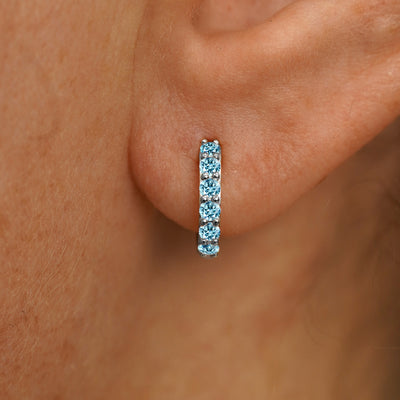 Close up view of a model's ear wearing a white gold Small Light Blue Lab Diamond Huggie Hoop