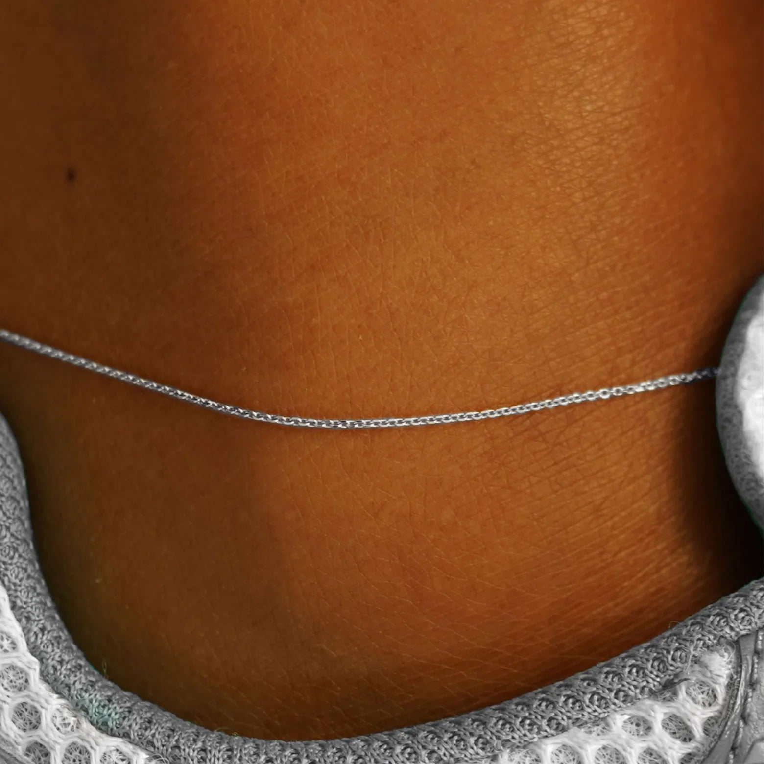 Close up view of a model's ankle wearing a white gold Cable Anklet