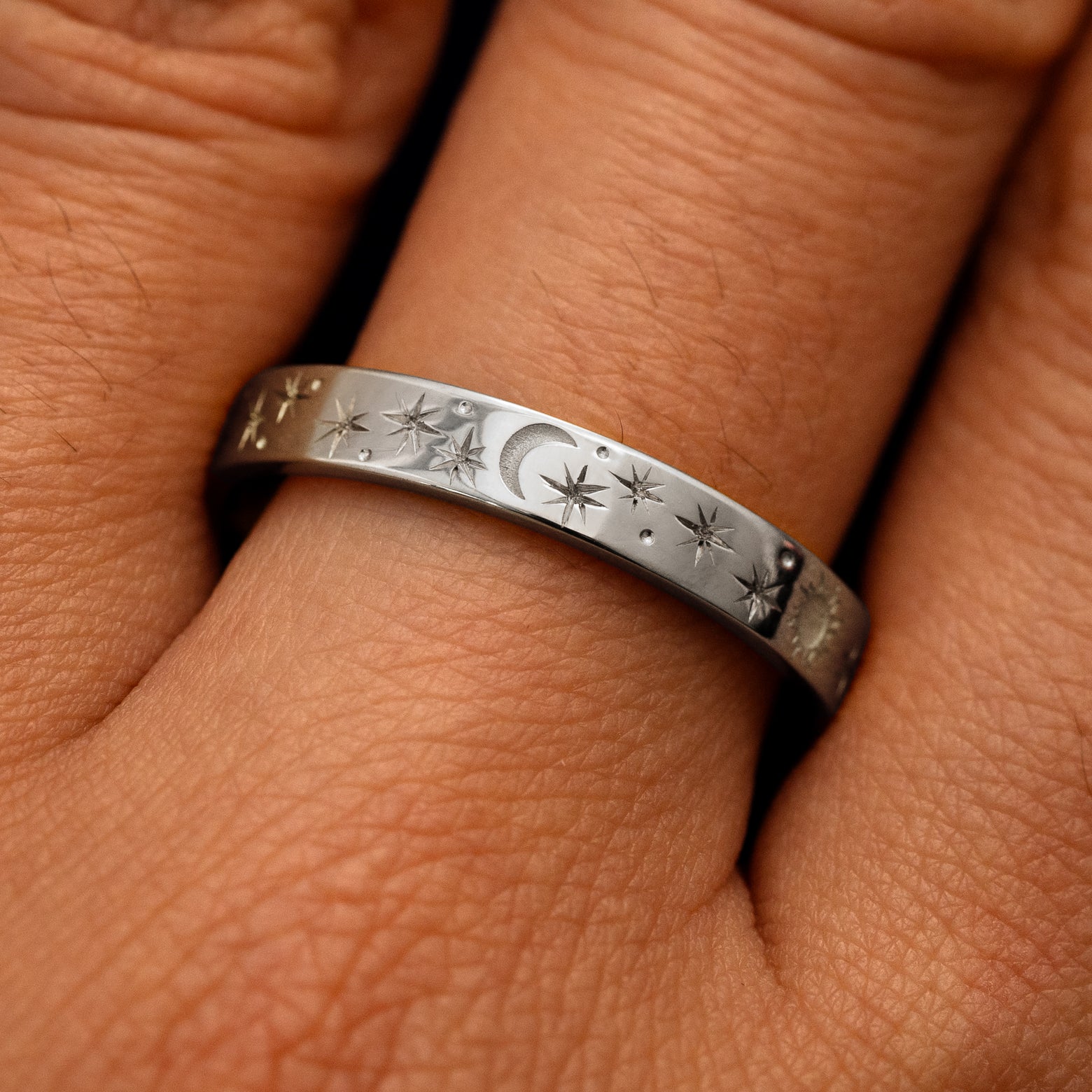 Close up view of a model's fingers wearing a 14k white gold Industrial Sun Moon and Stars Band