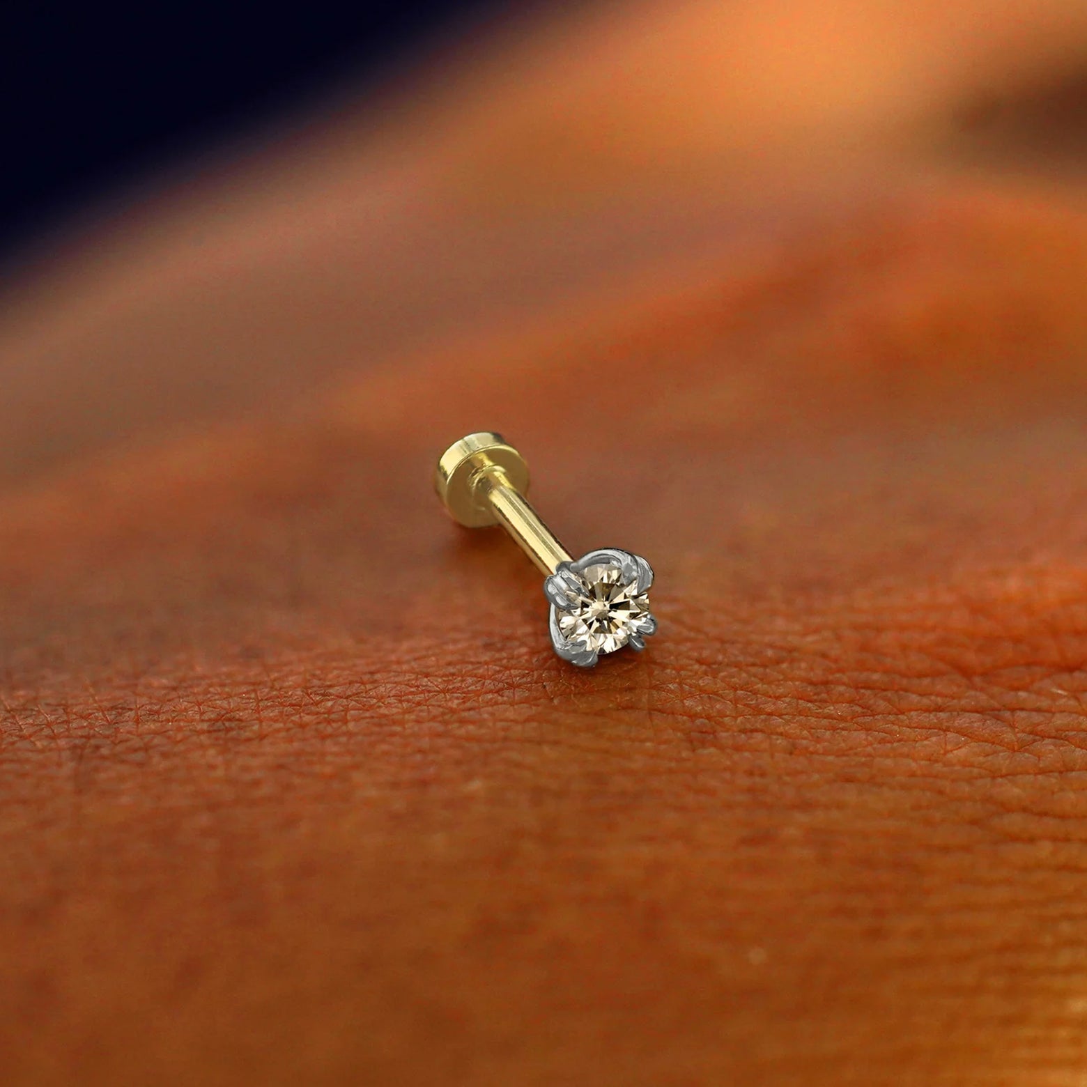 A solid 14k white gold Champagne Diamond Flatback Piercing resting on the back of a model's hand