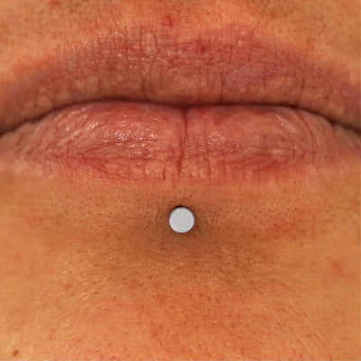 Close up view of a model's lips wearing a 14k white gold Mini Circle Flatback in a labret piercing