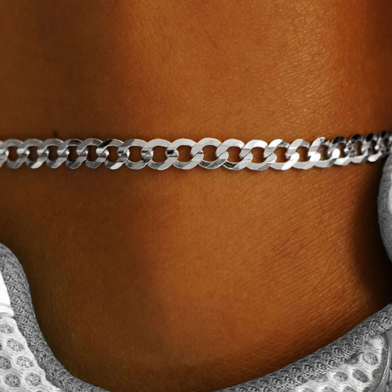 Close up view of a model's ankle wearing a 14k white gold Curb Anklet