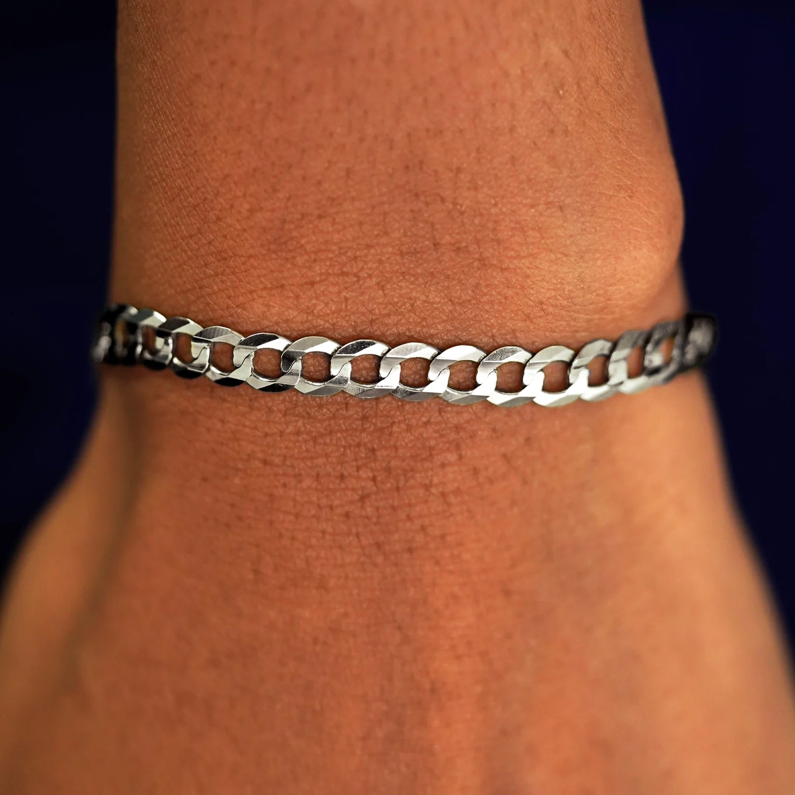 A model's wrist wearing a yellow gold Curb Chain Bracelet