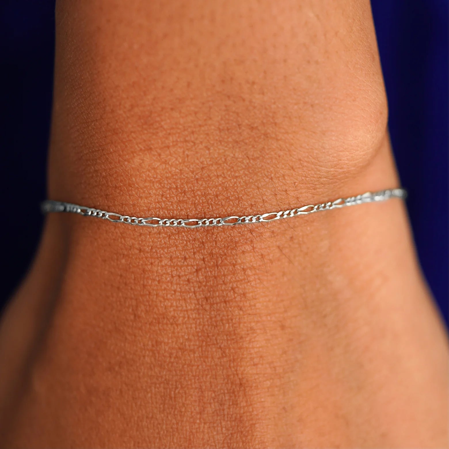Close up view of a model's wrist wearing a solid white gold Figaro Bracelet
