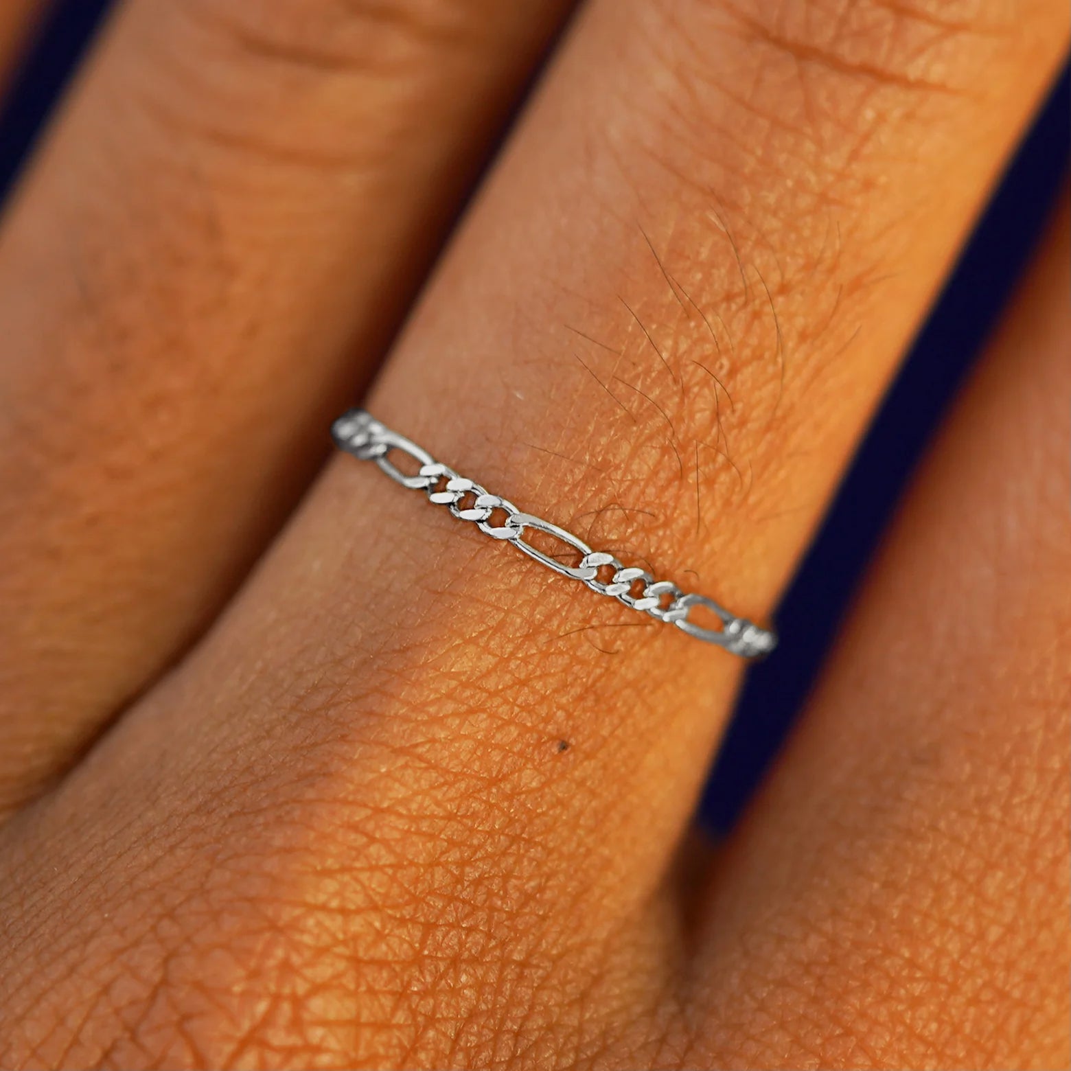 Close up view of a model's hand wearing a solid white gold Figaro Ring
