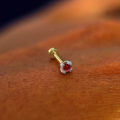 A solid 14k white gold Garnet Flatback Piercing resting on the back of a model's hand