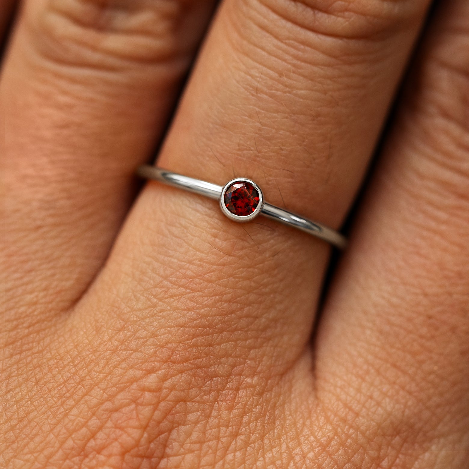 Close up view of a model's fingers wearing a 14k white gold Garnet Ring