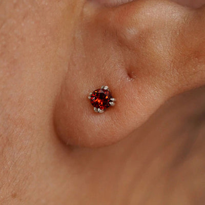 Close up view of a model's ear wearing a 14k white gold Garnet Earring