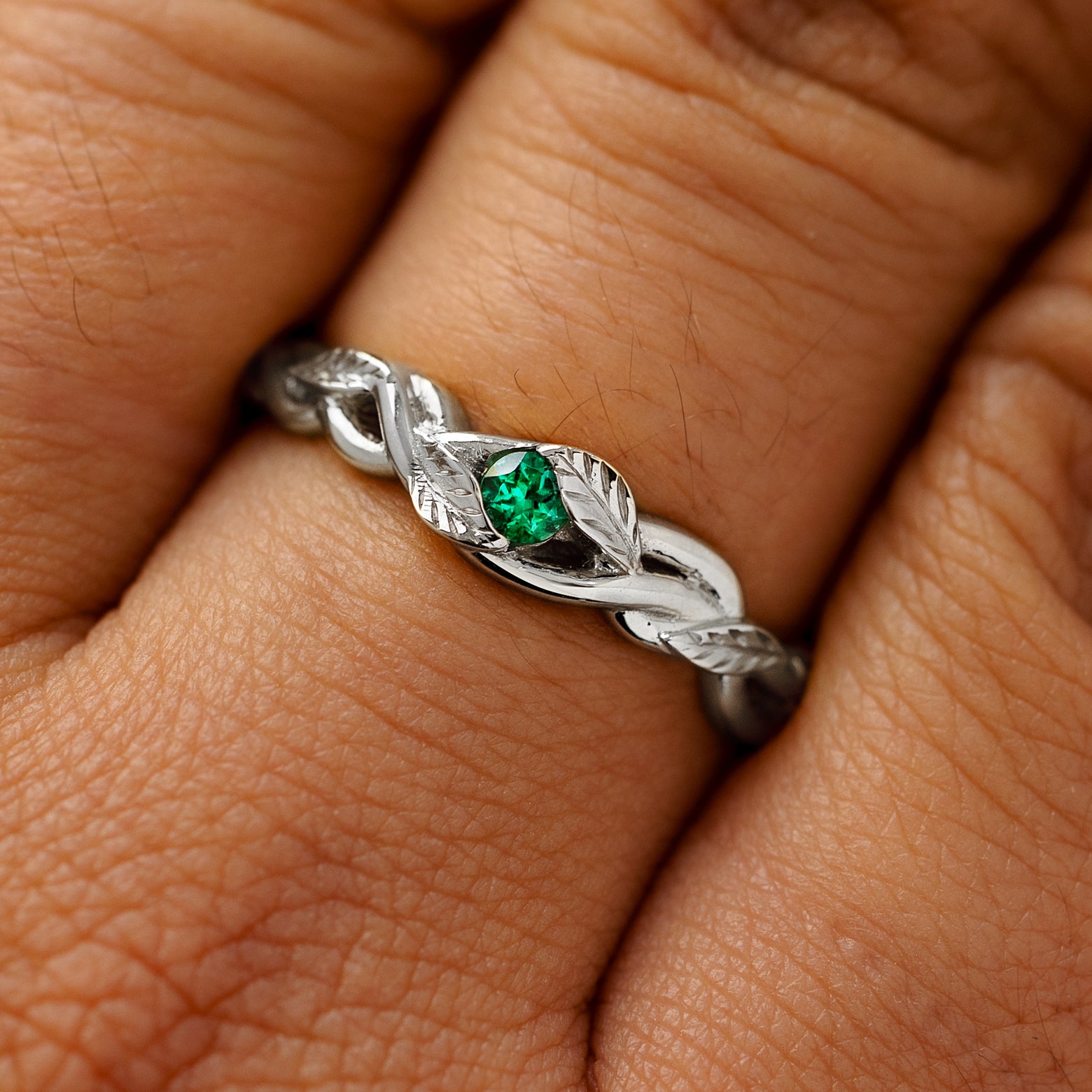 A solid 14k white gold emerald leaves and vines ring on a model's finger