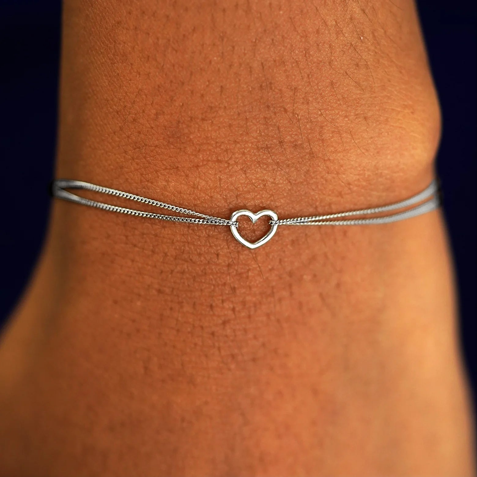 A model's wrist wearing a solid white gold Heart Bracelet