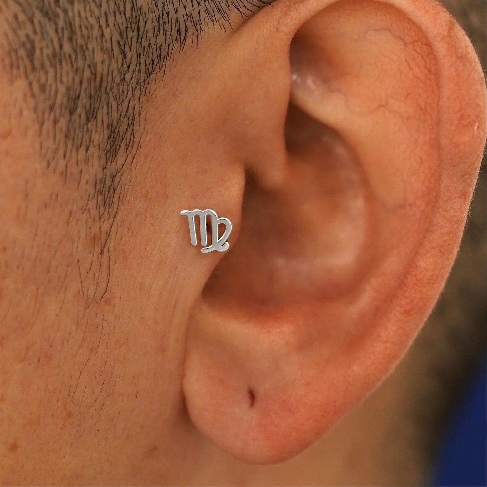 A model's ear wearing a 14k white gold Virgo Horoscope Flatback in a tragus piercing