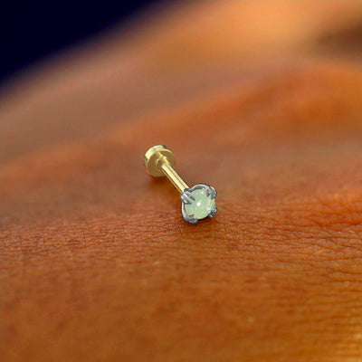 A solid 14k white gold Jade Flatback Piercing resting on the back of a model's hand